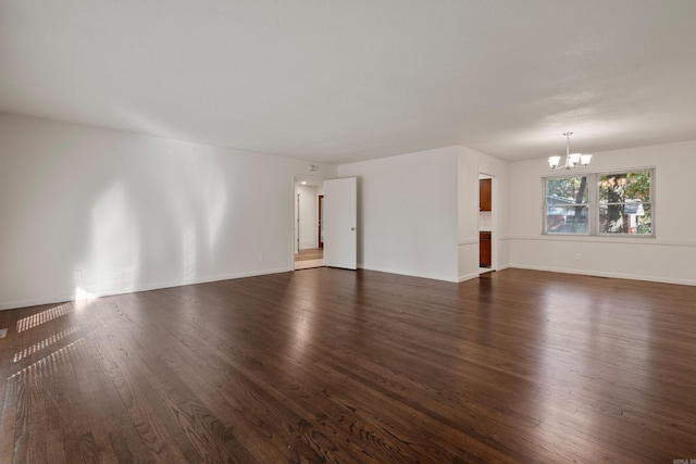 unfurnished room featuring a chandelier and dark wood-type flooring