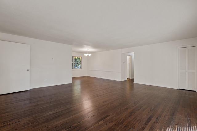 unfurnished room with an inviting chandelier and dark hardwood / wood-style floors