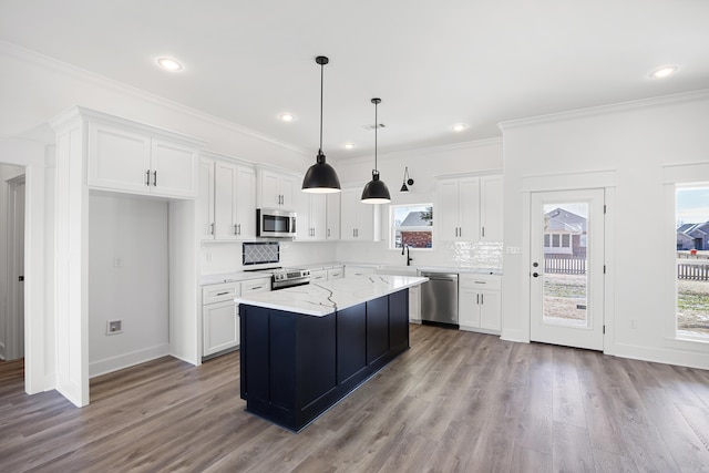 kitchen with white cabinets, light stone countertops, a kitchen island, and stainless steel appliances