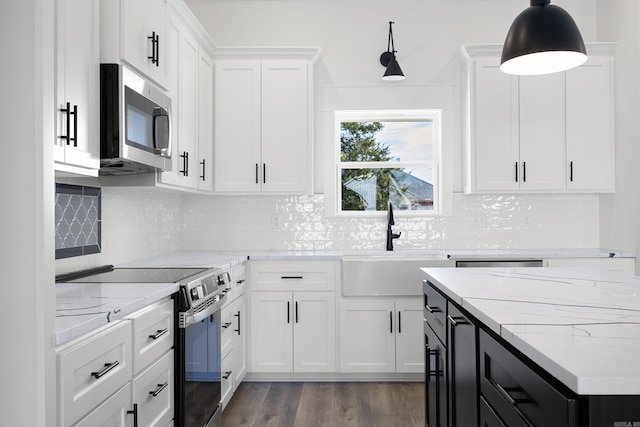 kitchen with stainless steel appliances, a sink, decorative light fixtures, and white cabinetry