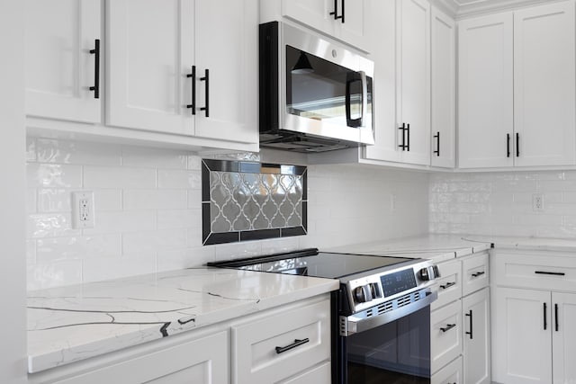 kitchen featuring stainless steel appliances, backsplash, white cabinetry, and light stone countertops