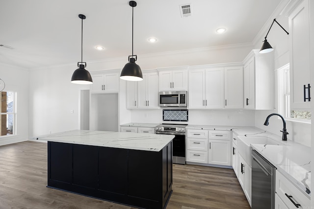 kitchen with appliances with stainless steel finishes, white cabinetry, and a center island