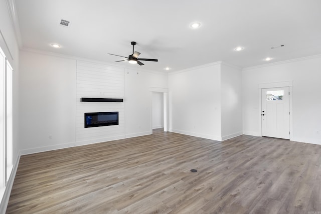 unfurnished living room with crown molding, a fireplace, light wood finished floors, and ceiling fan