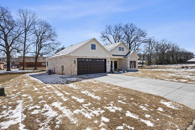 view of front of house featuring concrete driveway, brick siding, an attached garage, and central air condition unit