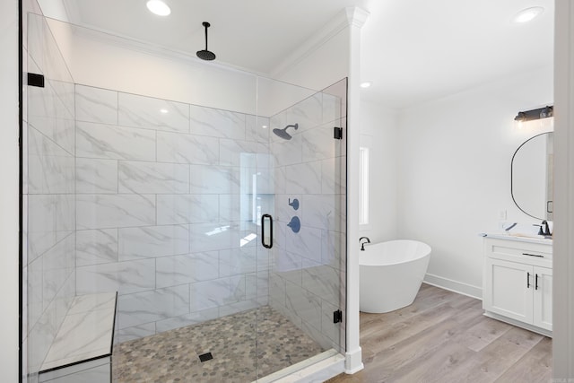 full bath featuring a stall shower, wood finished floors, crown molding, vanity, and a freestanding tub