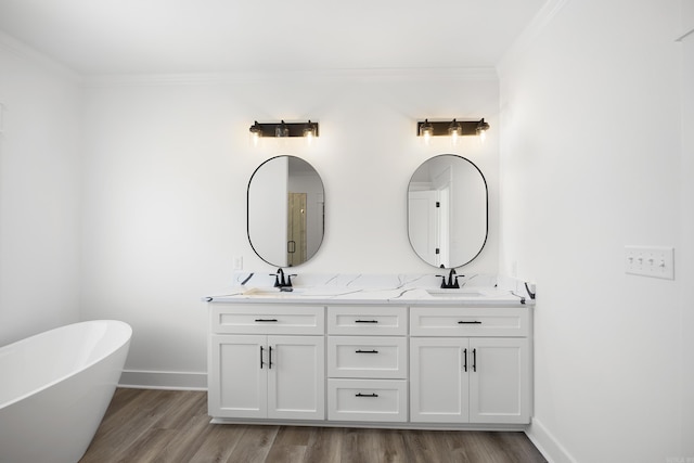 full bathroom with a soaking tub, crown molding, baseboards, and double vanity