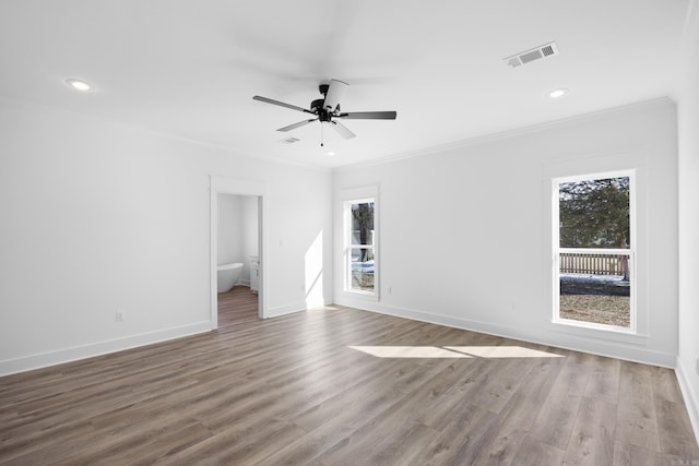 empty room featuring light wood finished floors, baseboards, visible vents, a ceiling fan, and ornamental molding