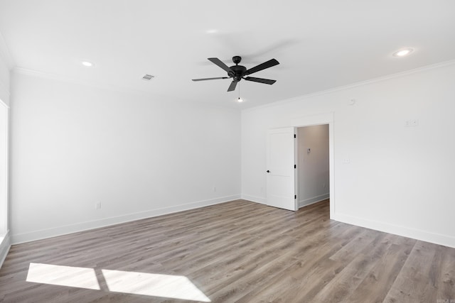 spare room with baseboards, light wood-type flooring, visible vents, and crown molding