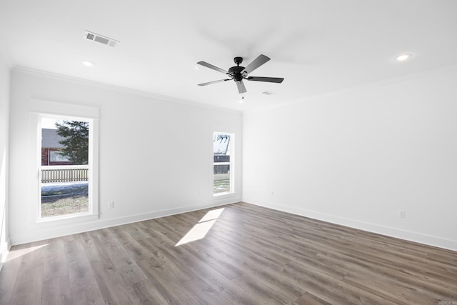 spare room featuring ornamental molding, visible vents, baseboards, and wood finished floors