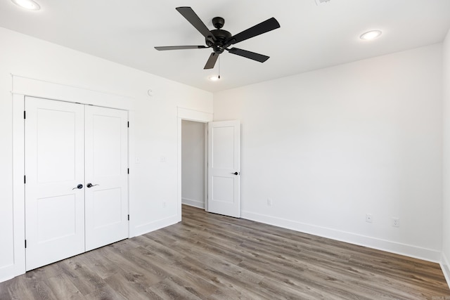 unfurnished bedroom with recessed lighting, a closet, baseboards, and wood finished floors