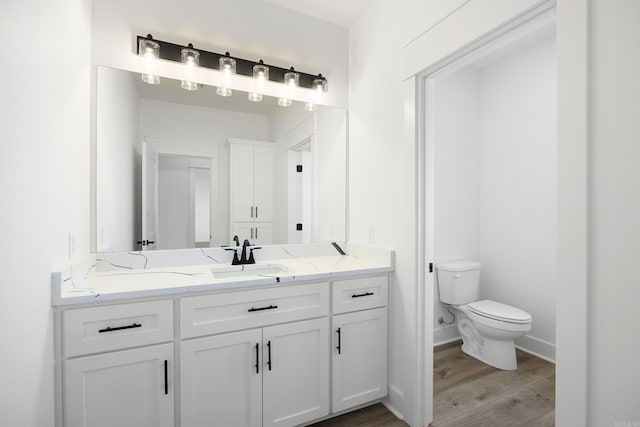 bathroom featuring baseboards, vanity, toilet, and wood finished floors