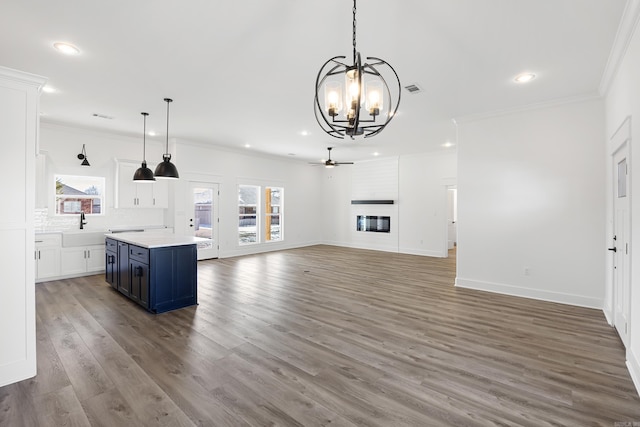 kitchen featuring blue cabinets, white cabinetry, open floor plan, light countertops, and decorative light fixtures