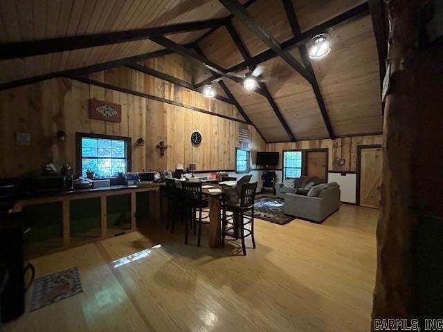 dining space featuring wooden walls, lofted ceiling with beams, light hardwood / wood-style flooring, and wood ceiling