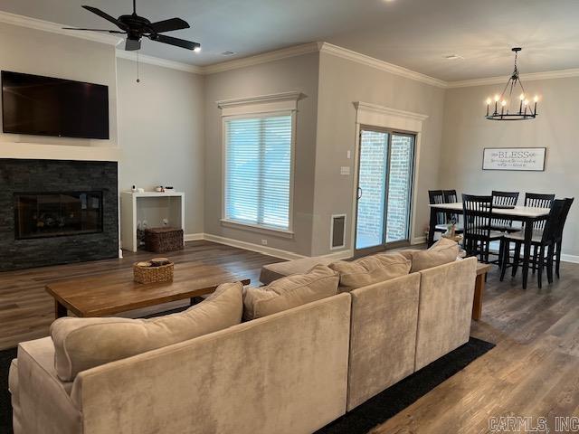 living room with wood-type flooring, ornamental molding, and ceiling fan with notable chandelier