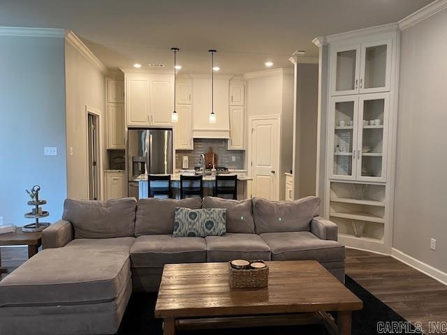 living room with dark hardwood / wood-style floors, crown molding, and sink