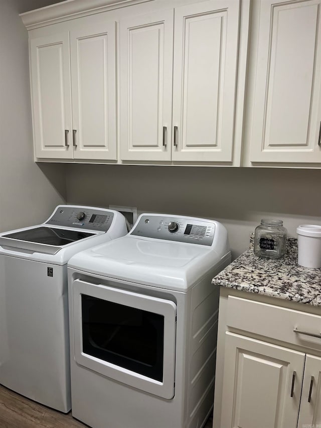 laundry area with cabinets, washing machine and dryer, and dark hardwood / wood-style floors