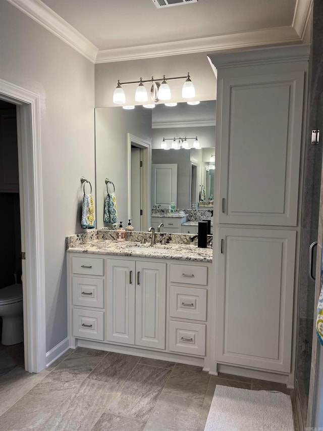 bathroom with ornamental molding, vanity, and toilet