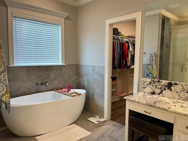 bathroom featuring ornamental molding, tile walls, vanity, and plus walk in shower