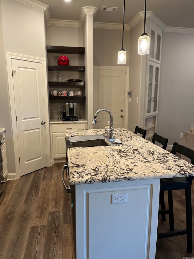 kitchen featuring dark wood-type flooring, a breakfast bar area, sink, white cabinetry, and decorative light fixtures