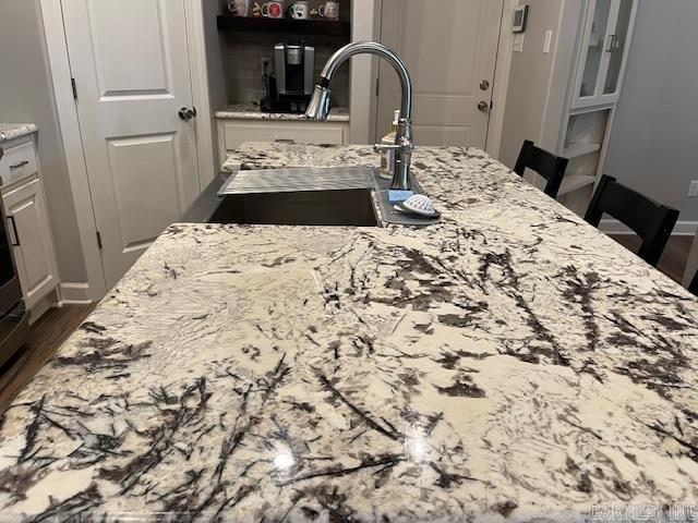 interior details with light stone countertops, sink, and a kitchen breakfast bar