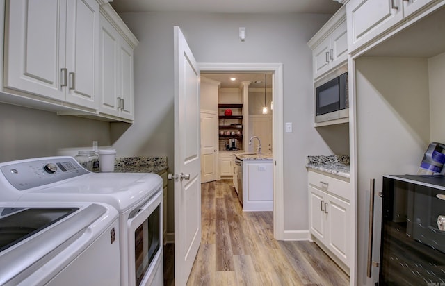 laundry area featuring cabinets, light hardwood / wood-style floors, sink, crown molding, and washing machine and dryer