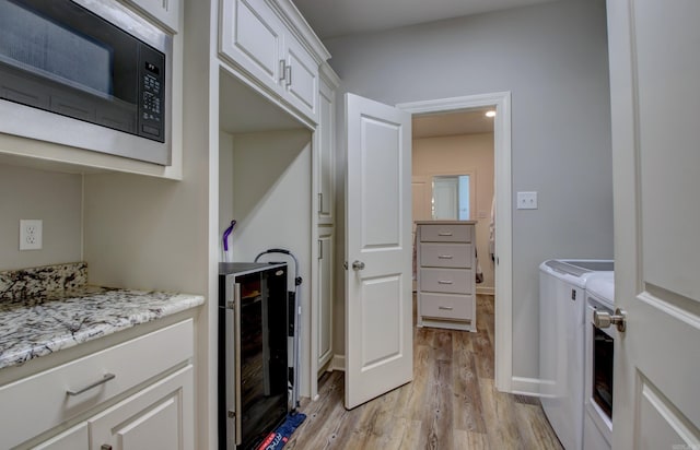 washroom with separate washer and dryer, light hardwood / wood-style floors, and wine cooler