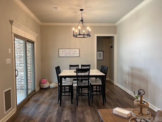 dining room with dark wood-type flooring, crown molding, and an inviting chandelier