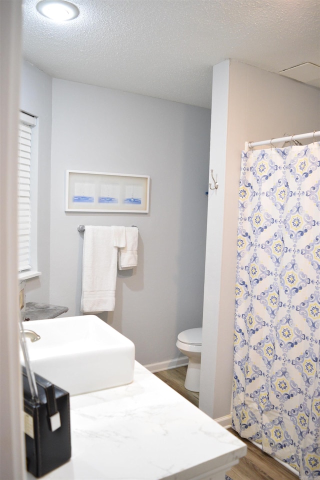 bathroom with sink, a textured ceiling, a shower with shower curtain, hardwood / wood-style floors, and toilet