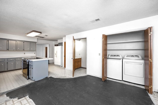 kitchen with white fridge with ice dispenser, separate washer and dryer, electric stove, gray cabinetry, and a center island