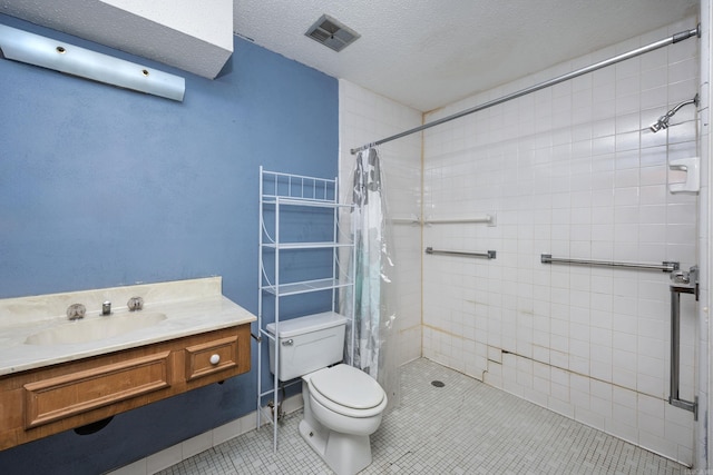 bathroom featuring a textured ceiling, walk in shower, toilet, vanity, and tile patterned floors