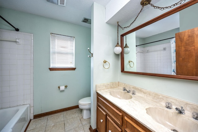 full bathroom featuring tile patterned floors, toilet, tiled shower / bath, vanity, and a textured ceiling