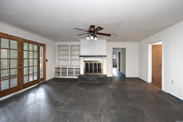 unfurnished living room featuring french doors, built in features, a textured ceiling, a brick fireplace, and ceiling fan