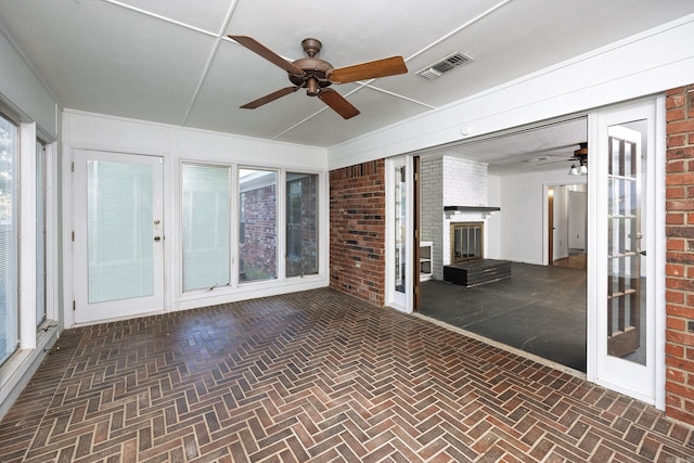 unfurnished sunroom with ceiling fan and a fireplace