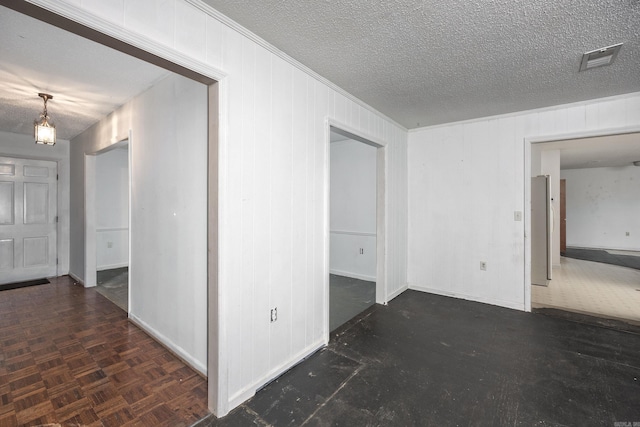 unfurnished room with a textured ceiling and dark parquet flooring