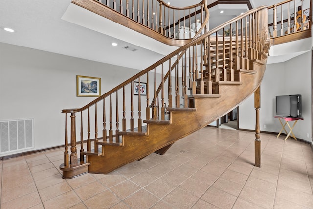 stairway featuring a towering ceiling and tile patterned flooring