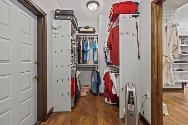 spacious closet featuring dark hardwood / wood-style floors and heating unit