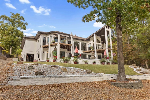 rear view of property featuring a lawn and a balcony