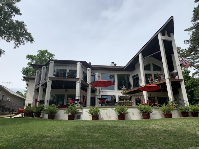 rear view of house featuring a balcony and a lawn