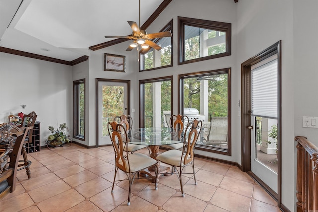 dining space with a high ceiling, crown molding, light tile patterned floors, and ceiling fan