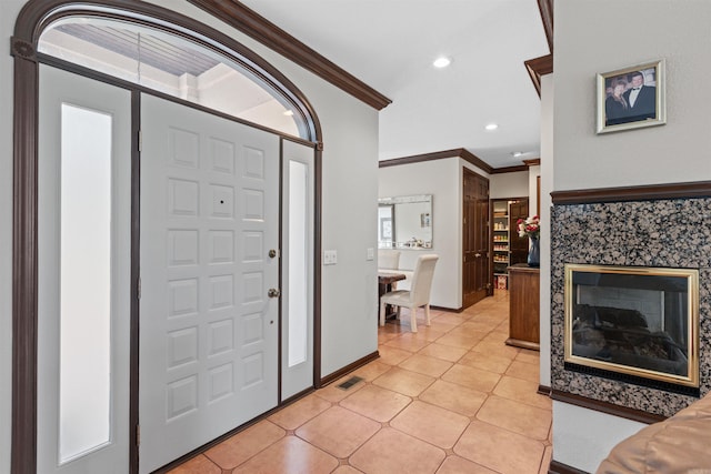 tiled foyer with a premium fireplace and ornamental molding