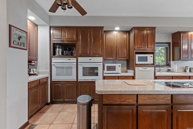 kitchen featuring sink, light stone countertops, light tile patterned floors, white appliances, and ceiling fan