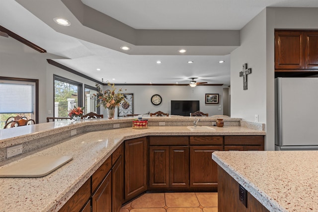 kitchen featuring white refrigerator, sink, light stone countertops, light tile patterned floors, and ceiling fan