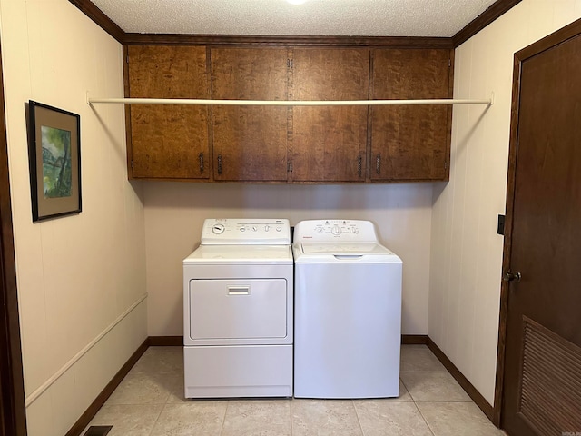 laundry area featuring cabinets, a textured ceiling, washing machine and dryer, and crown molding