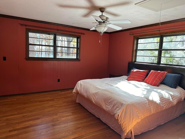 bedroom featuring wood-type flooring, multiple windows, ornamental molding, and ceiling fan