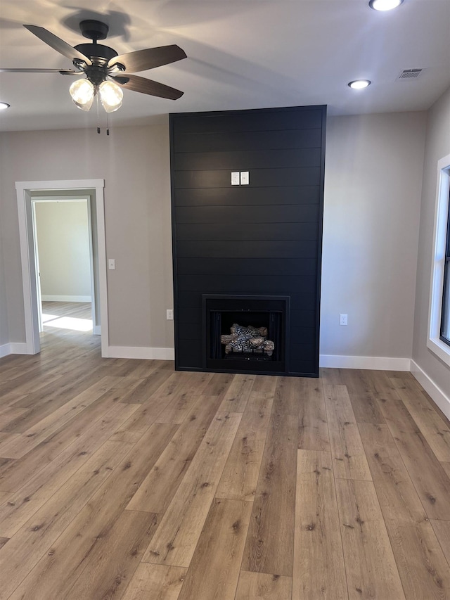 unfurnished living room with ceiling fan, light wood-type flooring, and a fireplace