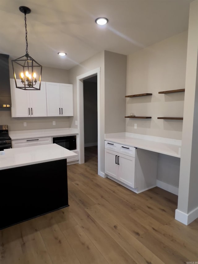 kitchen with white cabinetry, hanging light fixtures, light wood-type flooring, stainless steel range oven, and wall chimney exhaust hood