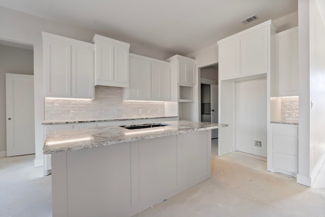 kitchen featuring light stone counters, tasteful backsplash, white cabinets, and a kitchen island