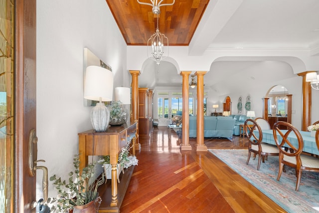 interior space featuring crown molding, a notable chandelier, ornate columns, and dark hardwood / wood-style flooring