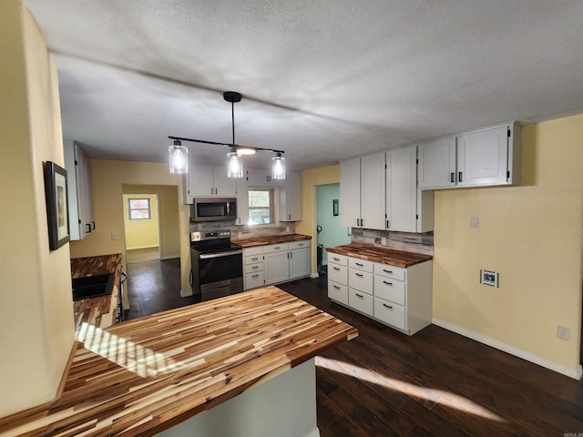 kitchen with hanging light fixtures, wood counters, white cabinets, appliances with stainless steel finishes, and dark hardwood / wood-style flooring