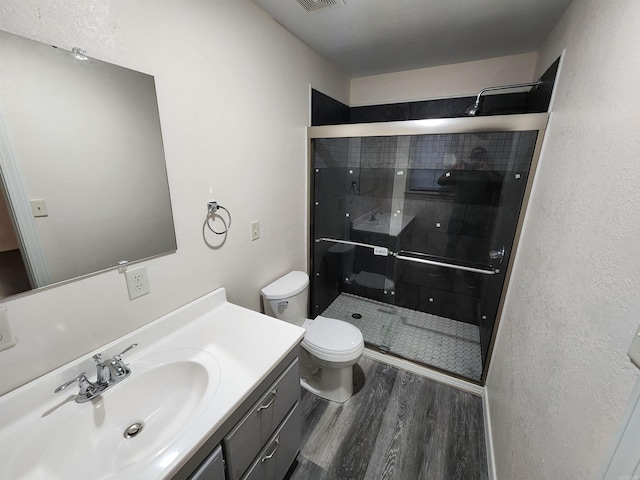 bathroom with toilet, a shower with shower door, vanity, and wood-type flooring